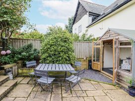 A garden with a table and chairs by a shed at Rushmoor Cottage in Colaton Raleigh