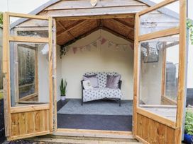 A greenhouse with a couch and potted plant at Rushmoor Cottage, Colaton Raleigh