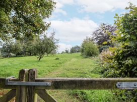 A gate opening to a grassy area with trees at Rushmoor Cottage in Colaton Raleigh