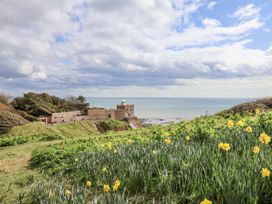 A view of the sea and a building surrounded by flowers at Rushmoor Cottage in Colaton Raleigh
