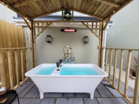 An outdoor bath area with a bathtub under a wooden structure at Klysa in Camborne