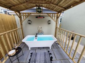 An outdoor area with a bathtub and heater at Klysa Camborne