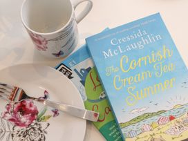 A cup, fork, plate, book and magazine on a table at Baker Chambers in Camborne