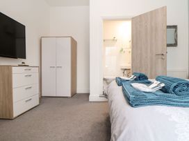 A bedroom with a television, chest of drawers, and towels at Teylu in Camborne
