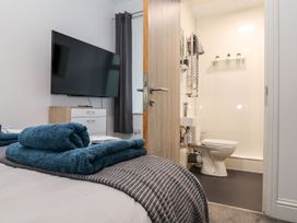 A bedroom with a television and attached bathroom at Teylu in Camborne
