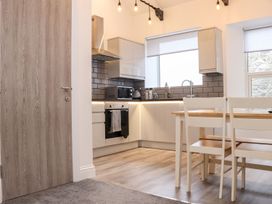 A kitchen with cabinets, stove, and dining table at Battell Chambers in Camborne