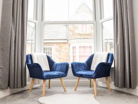 A living room with two blue armchairs and grey curtains at Battell Chambers in Camborne