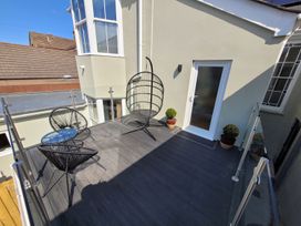 An outdoor patio with a hanging chair and a coffee table at Daniel Chambers in Camborne