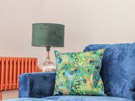 A living room featuring a blue sofa with a patterned pillow and a green lamp at Mews Retreat in Camborne