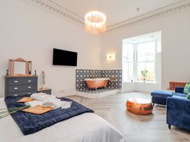 A bedroom with a bathtub and a sofa at Mews Retreat in Camborne