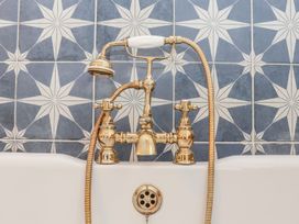 A bathtub with a gold faucet and shower head at Mews Retreat in Camborne