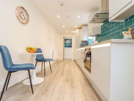 A kitchen with a clock, table, chairs, and kitchen appliances at Mews Retreat Camborne