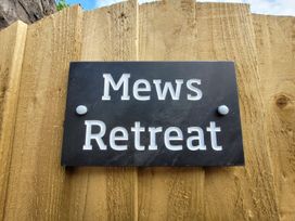 A sign for Mews Retreat on a wooden fence at Mews Retreat in Camborne