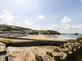 A beach view with cliffs and houses at Mews Retreat in Camborne