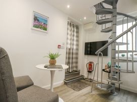 A snug area with a spiral staircase and a flat-screen TV at The Snug in Camborne