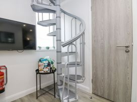 A hallway with a spiral staircase and a television at The Snug in Camborne