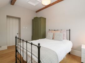 A bedroom with a bed, wardrobe, and bedside table at Spring View in Tetbury