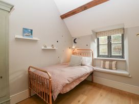 A bedroom with a bed, shelves, and a window seat at Spring View in Tetbury