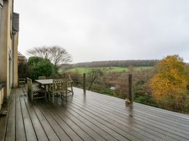 An outdoor deck with a table and chairs overlooking hills at Spring View in Tetbury