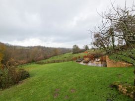 A landscaped outdoor area with a seating patio and trees at Spring View in Tetbury