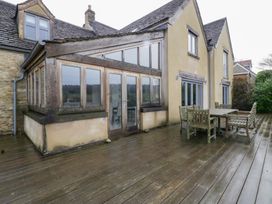 A house exterior with a wooden deck and dining set at Spring View in Tetbury