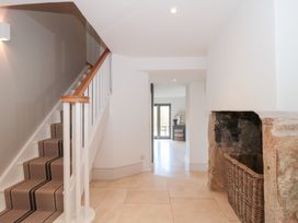 A hallway with a staircase and a basket at Spring View in Kingscote, Gloucestershire