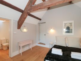 A bedroom with a bed and a bathroom door at Spring View in Kingscote, Gloucestershire