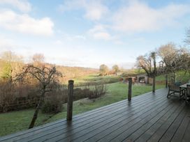 A garden view with decking and trees at Spring View, Kingscote, Gloucestershire
