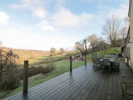 A decking area with table and chairs overlooking hills at Spring View in Kingscote, Gloucestershire