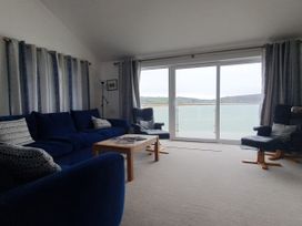 A living room with a view of the water at Gilfach Goed in Pwllheli