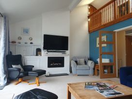 A living room with a television and fireplace at Gilfach Goed in Pwllheli