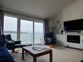 A living room with a sofa and armchair facing a view at Gilfach Goed Pwllheli