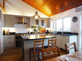 A kitchen with an island and stools at Gilfach Goed in Pwllheli