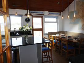 A kitchen with a dining area and flowers on the table at Gilfach Goed in Pwllheli