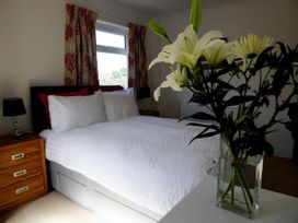 A bedroom with a bed and flowers on a table at Gilfach Goed Pwllheli