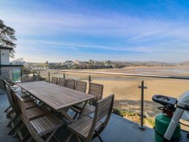 A dining area with a table and chairs on a balcony at Gilfach Goed in Abersoch