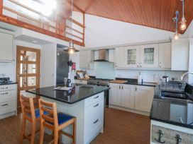 A kitchen with a central island and bar stools at Gilfach Goed, Abersoch