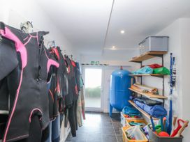 A utility room with wetsuits hung on a rack at Gilfach Goed in Abersoch