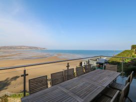 An outdoor terrace with a table and chairs overlooking the sea at Gilfach Goed in Abersoch