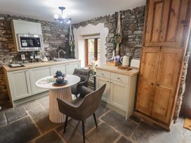 A kitchen with stone walls and wooden cabinets at Gwyn Studio in Aberdare