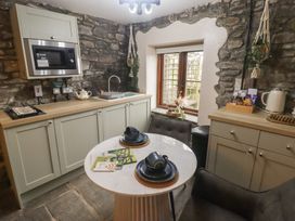 A kitchen with cabinets, a sink, and a table at Gwyn Studio in Aberdare