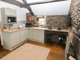 A kitchen with stone wall and bar stools at Glas Studio in Aberdare