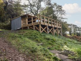 A wooden deck next to a metal structure surrounded by grass at Glas Studio in Aberdare