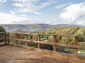 A deck with a wooden railing overlooking hills and a valley at Glas Studio in Aberdare