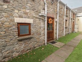 An outdoor area with stone wall, wooden door, and pathway at Arian in Aberdare