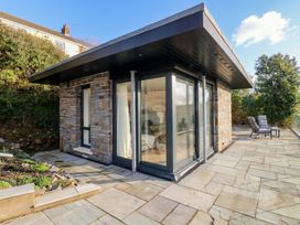 A garden with a stone building and patio at Awelfryn