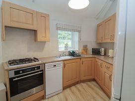 A kitchen with cabinets, sink, and oven at Round Barn in Ilfracombe