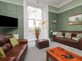 A living room with brown sofas and a television at 8 Corkickle in Whitehaven