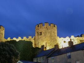 A castle wall illuminated at dusk in Conwy