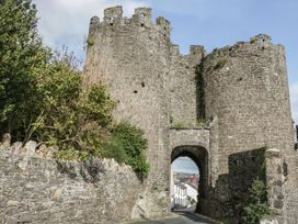 A castle with stone walls and an archway on a road at Riverside Cottage in Conwy